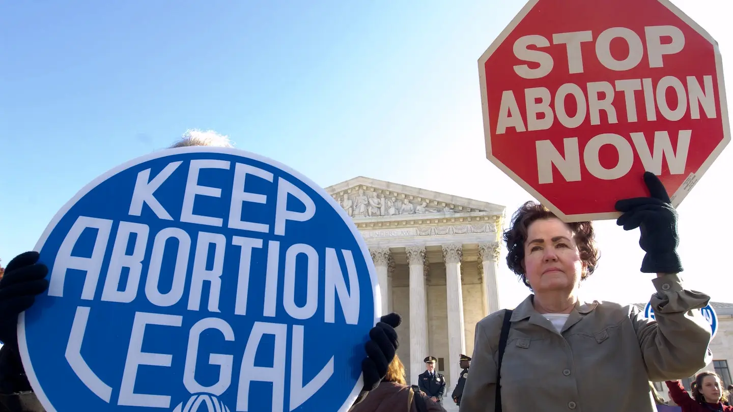 Two signs at a political rally: "Keep abortion legal" and "Stop abortion now"